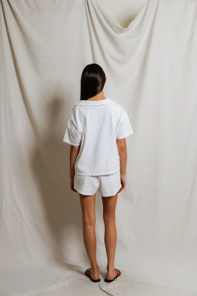 Back view of white cropped polo top showing boxy silhouette and relaxed short sleeve, paired with white mini shorts and flip sandals — perfectwhitetee Charlie Tennessee Jersey Polo