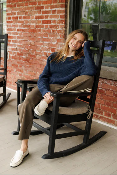 perfectwhitetee Claud Pureform Cropped Pant with Stripes in dark olive — seated lifestyle view styled with a navy knit sweater