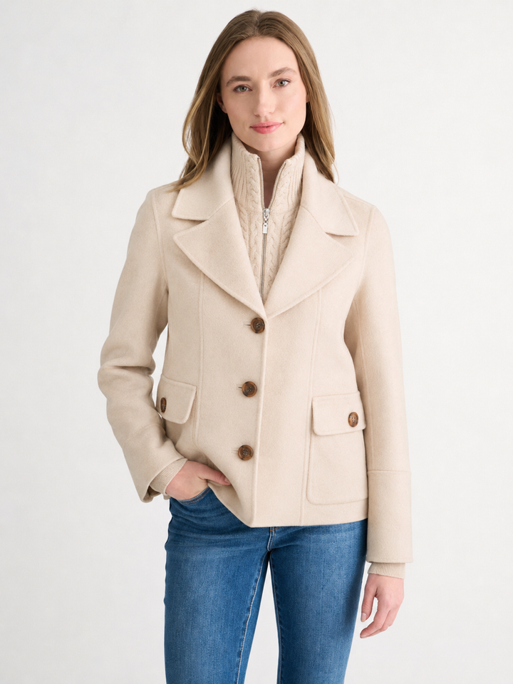 Woman wearing a sandstone wool-cashmere coat with a cable knit collar insert and wooden buttons.
