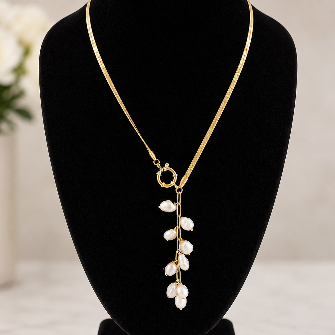 Gold necklace with pearl-like pendants on a black mannequin bust.