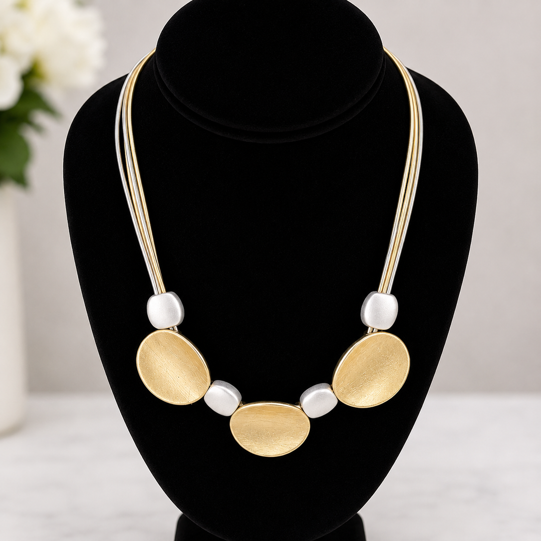 Necklace with gold and white circular pendants on a black mannequin bust.