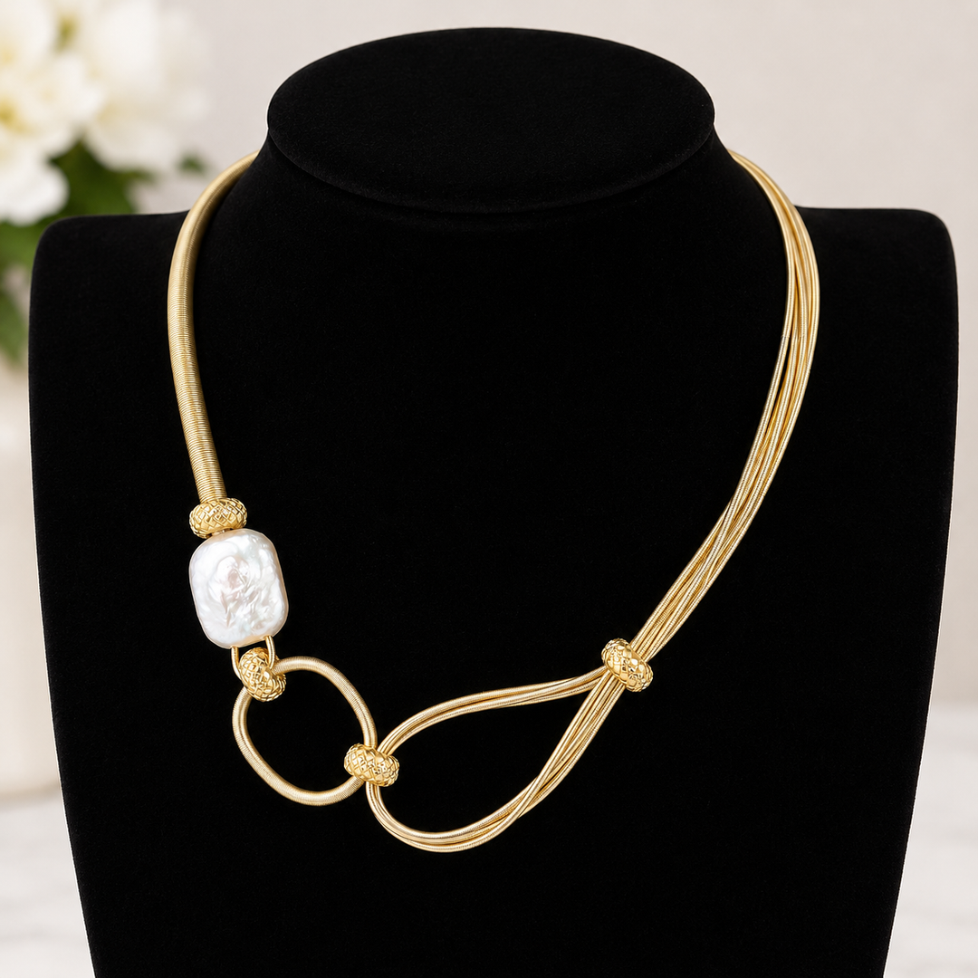 Gold necklace with a large freshwater pearl pendant on a black stand.