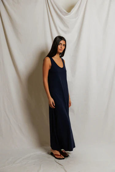 Side view of navy sleeveless maxi dress showing straight relaxed silhouette and slight skirt flare at hem, styled with black slide sandals — perfectwhitetee Jasmine Cotton Maxi Dress in Navy