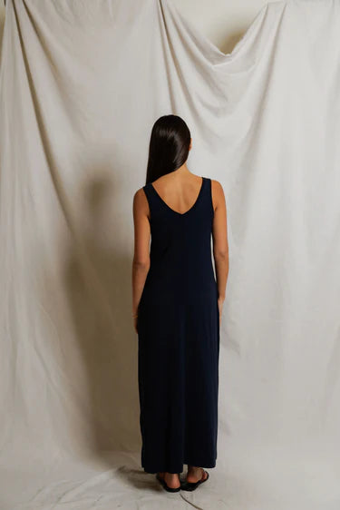 Back view of navy sleeveless maxi dress showing straight relaxed silhouette and slight skirt flare at hem, styled with black slide sandals — perfectwhitetee Jasmine Cotton Maxi Dress in Navy