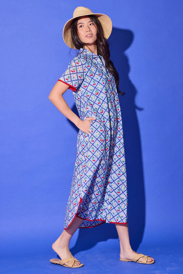 Alden Adair Josie Midi Dress, side view in light blue cherry print showing the side seam pocket, side slit at the hem, and red contrast trim.