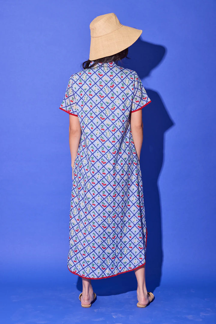 Alden Adair Josie Midi Dress, back view in light blue cherry-and-floral lattice print, showing the relaxed column shift shape, short sleeves with red cuff trim, and red-trimmed hem.