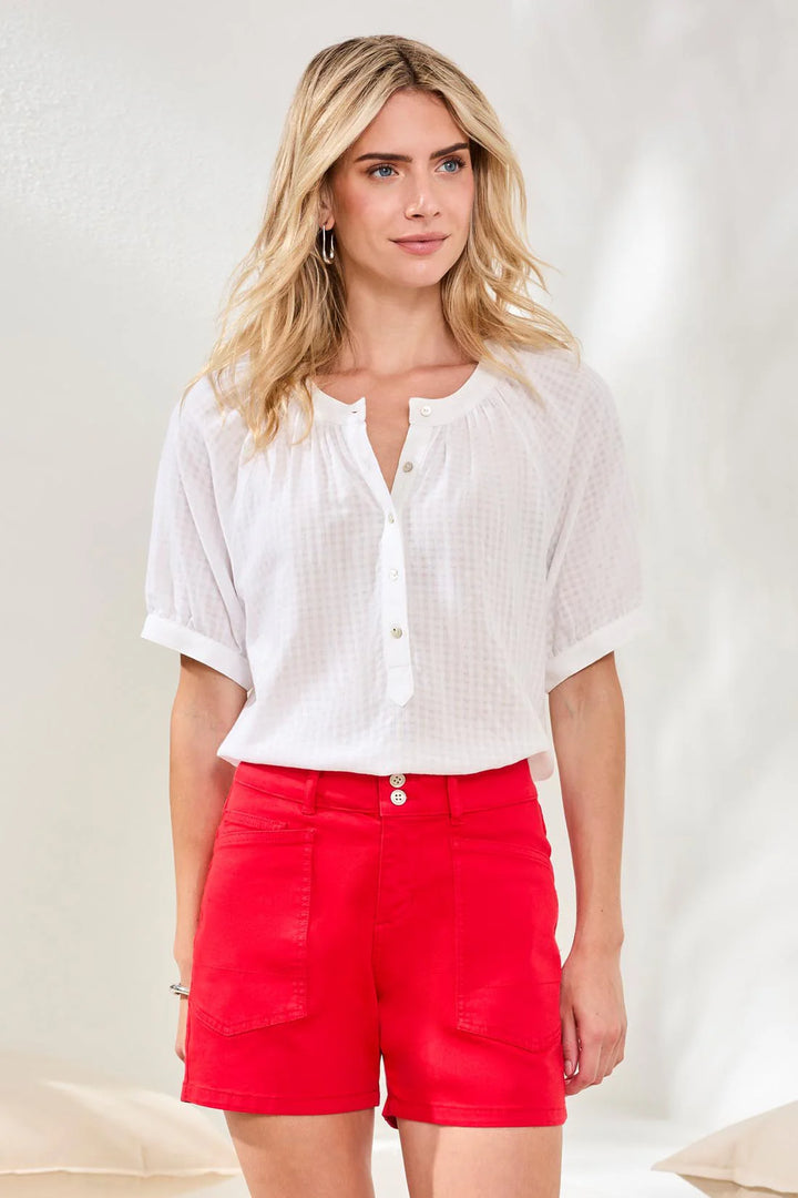 Model wearing Tribal Comfort Stretch Fly Front Short in sangria red, mid-rise five-pocket denim short with double button fly, styled with a white linen blouse.