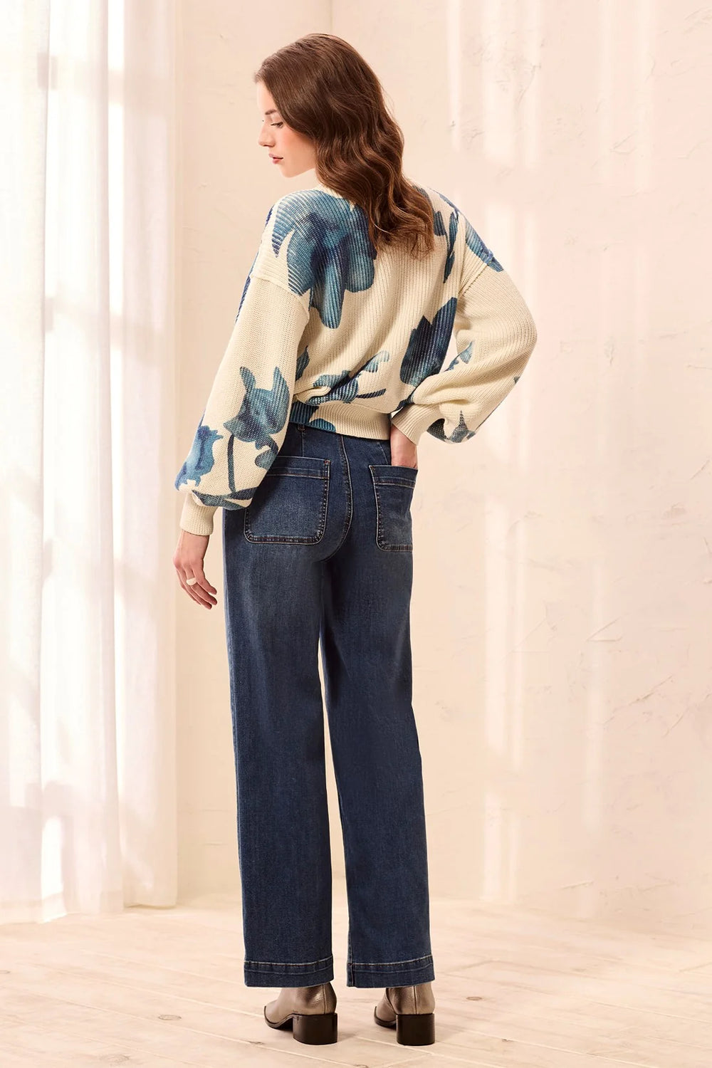 Full-body back view of the same model, showing the jeans' back patch pockets with snap closures and straight leg silhouette.