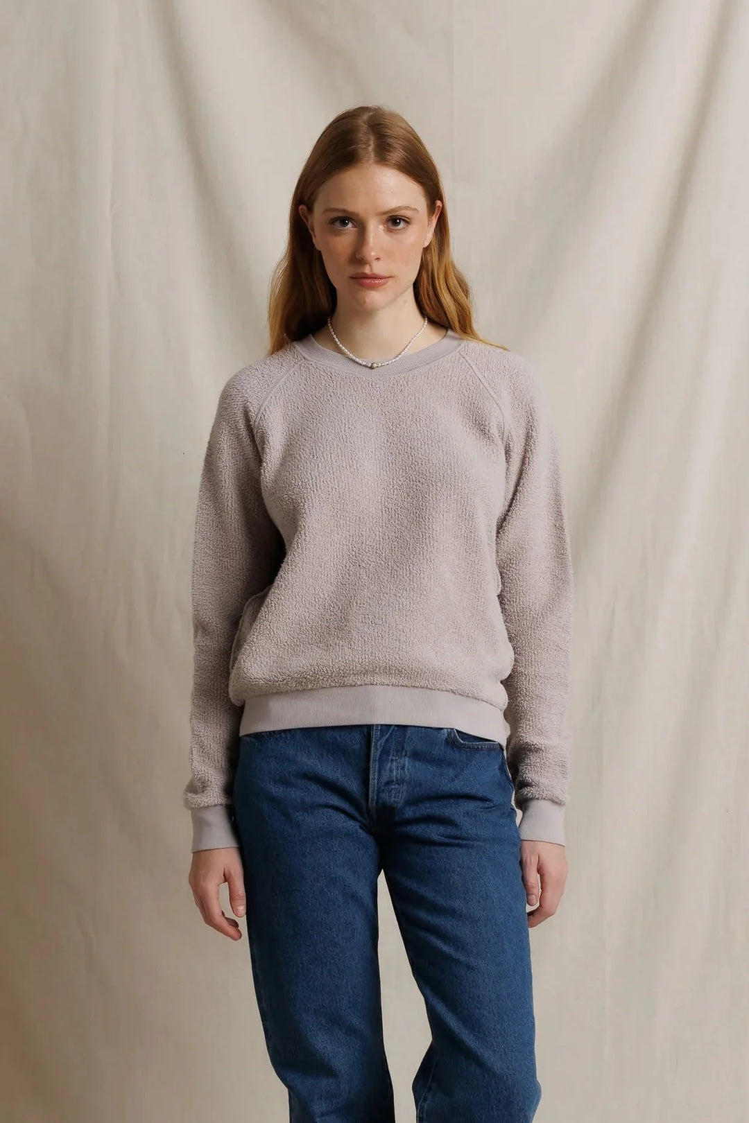 perfectwhitetee Ziggy Inside Out Fleece Sweatshirt in Cloud Gray, front view on model, showing a textured looped fleece crewneck with raglan sleeves and smooth ribbed trim, styled with medium-wash jeans and a pearl necklace