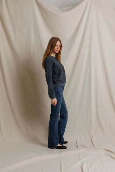 Side profile view of the model wearing the crewneck sweatshirt with flared jeans and black flats.